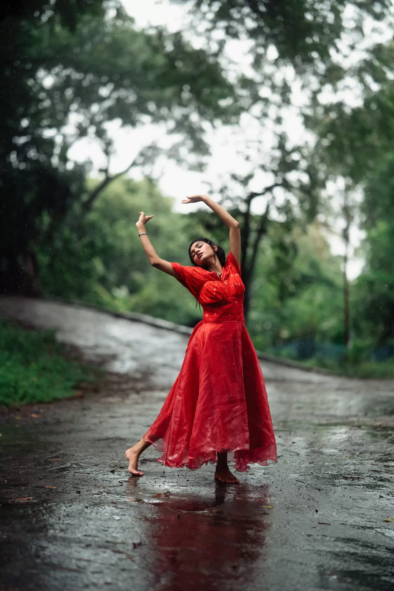 Graceful outdoor dance pose in red dress on a winding road