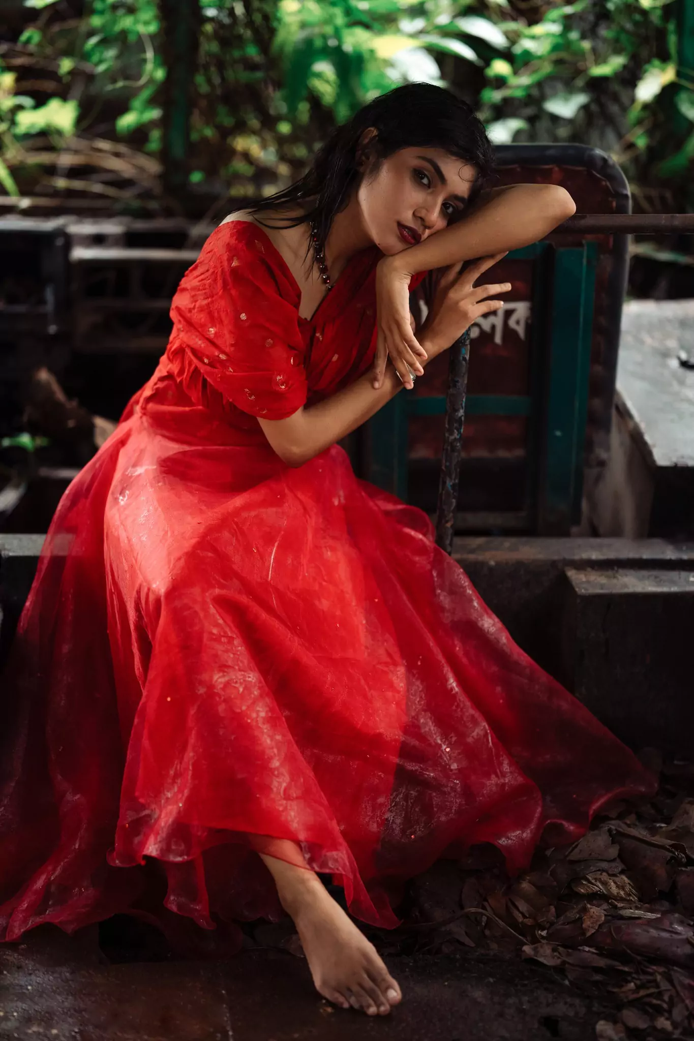 Elegant pose in a red dress in a serene garden setting