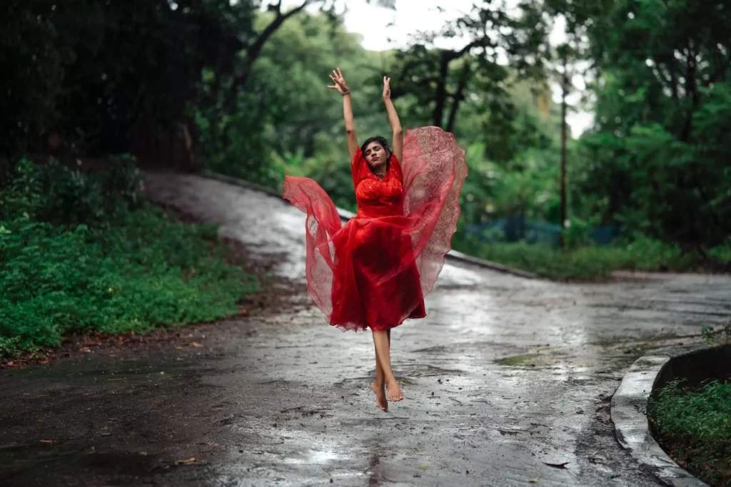 Energetic leap in a red gown on a picturesque forest road
