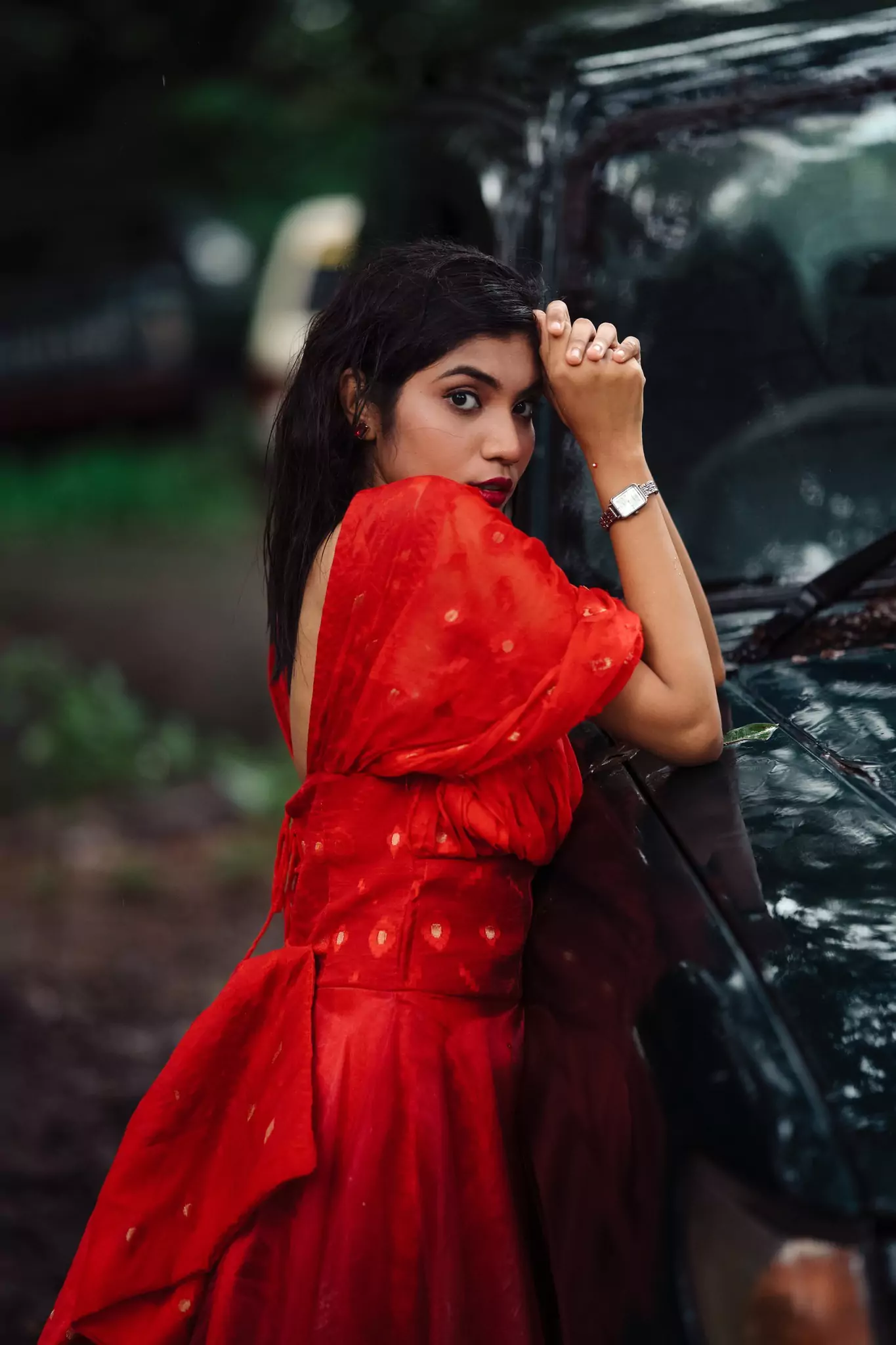 Elegant side pose in a detailed red dress by a parked car