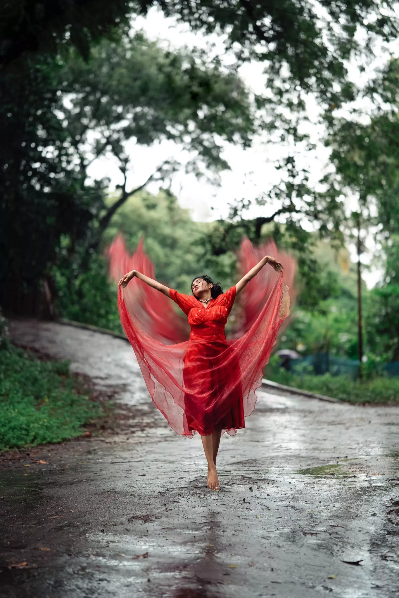 Dramatic movement, red dress spread wide, mid-spin on a forest path