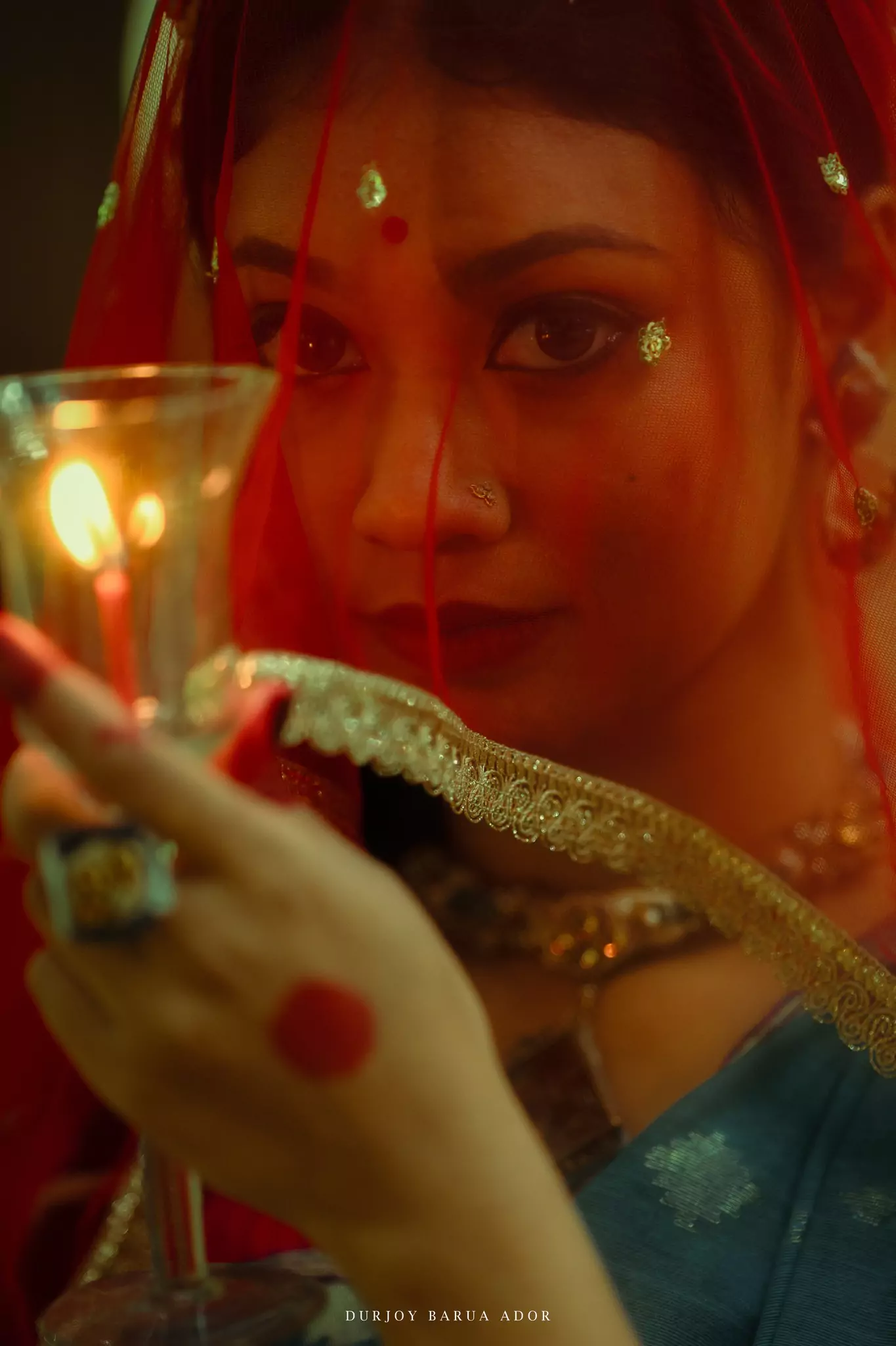 Cinematic close-up of woman’s face and hands holding a diya with intense expression.